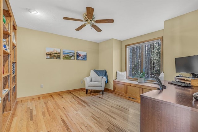 office area with baseboards, light wood-type flooring, and ceiling fan