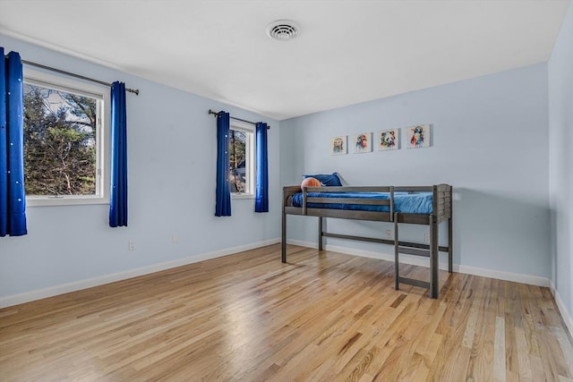 bedroom featuring visible vents, baseboards, and light wood finished floors