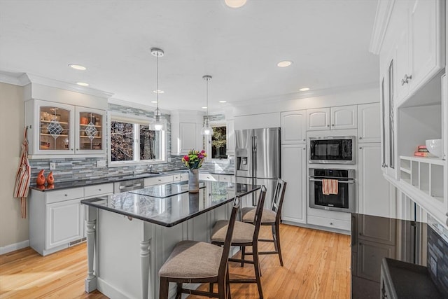 kitchen featuring crown molding, a kitchen breakfast bar, white cabinets, and appliances with stainless steel finishes