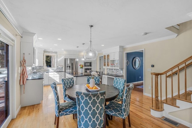 dining area with stairway, visible vents, light wood-style flooring, and crown molding