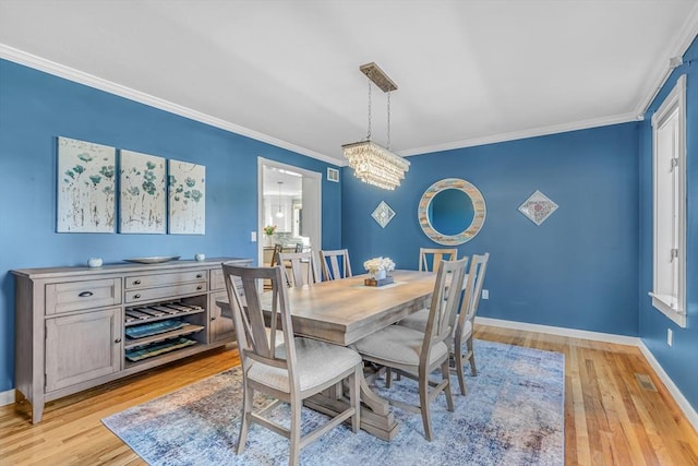 dining room with visible vents, ornamental molding, light wood-style floors, an inviting chandelier, and baseboards