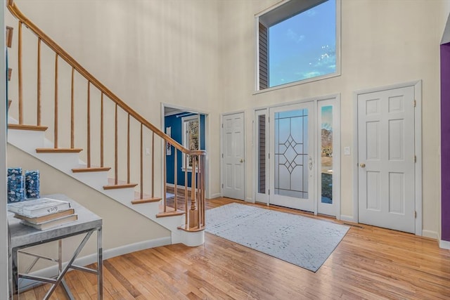 entryway with stairs, a high ceiling, wood finished floors, and baseboards