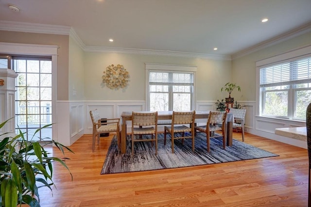 dining space with healthy amount of natural light, light wood finished floors, a decorative wall, a wainscoted wall, and recessed lighting