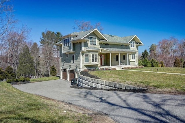 victorian-style house featuring driveway, a garage, a porch, and a front lawn