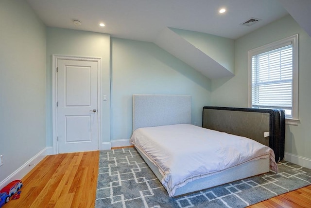 bedroom with wood finished floors, baseboards, recessed lighting, and vaulted ceiling