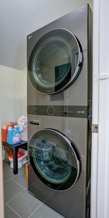 clothes washing area with stacked washing machine and dryer and tile patterned flooring