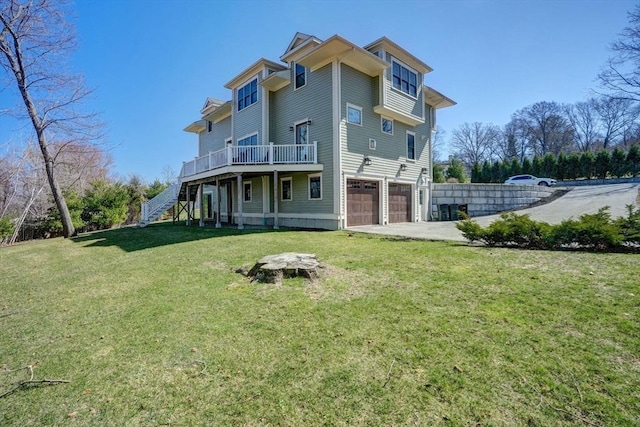 rear view of property featuring stairs, a garage, a wooden deck, concrete driveway, and a lawn