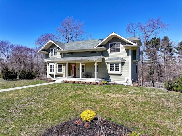 traditional home featuring covered porch, a front lawn, and a shingled roof