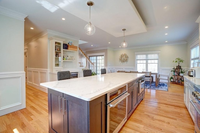 kitchen with a decorative wall, oven, open shelves, light wood-style floors, and a kitchen island