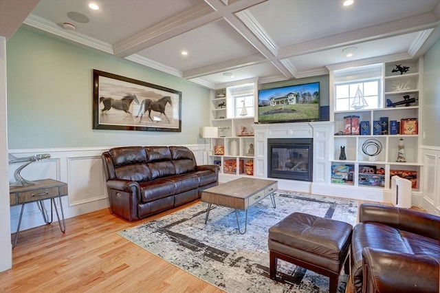 living area with wood finished floors, a glass covered fireplace, built in features, beam ceiling, and a decorative wall