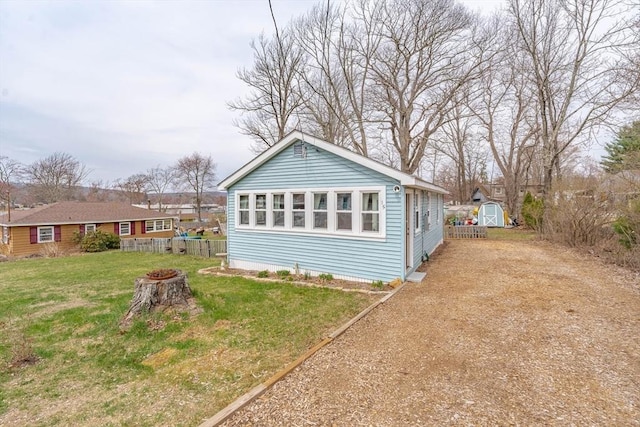 exterior space with a lawn, a fire pit, fence, an outbuilding, and a storage unit