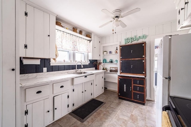 kitchen with a ceiling fan, a sink, electric range, white cabinetry, and freestanding refrigerator