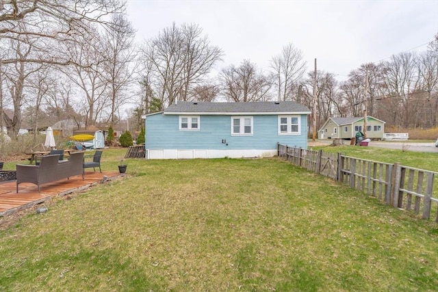 back of house with a lawn, a wooden deck, and fence