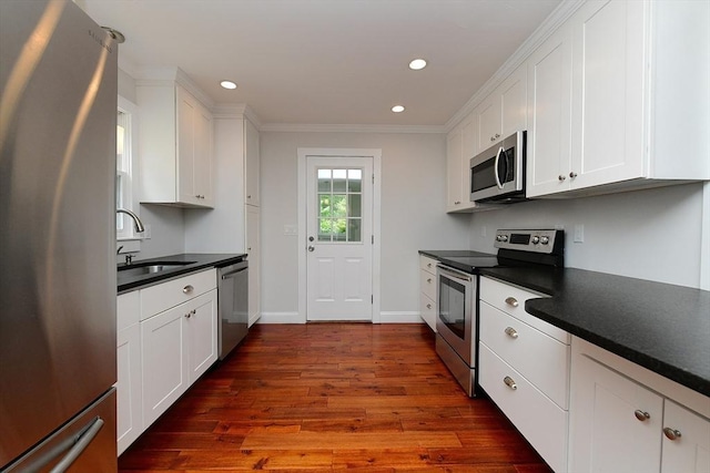 11 Winchester Ave, Bourne, MA 02532 - kitchen featuring appliances with stainless steel finishes, a sink, dark countertops, white cabinets, and crown molding