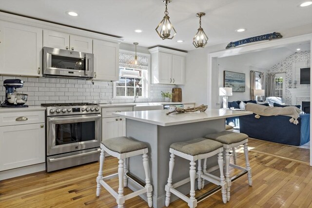 21 Grove St, Fairhaven, MA 02719 - kitchen featuring appliances with stainless steel finishes, a kitchen bar, white cabinets, open floor plan, and lofted ceiling