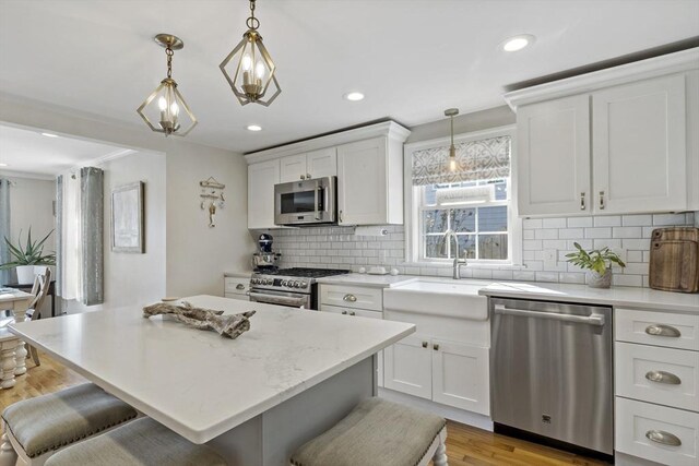 21 Grove St, Fairhaven, MA 02719 - kitchen featuring appliances with stainless steel finishes, a kitchen breakfast bar, backsplash, white cabinetry, and recessed lighting