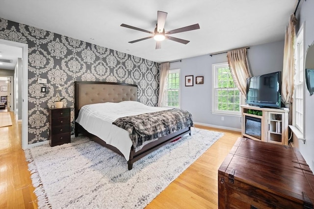 126 Arrow Head Rd, Marshfield, MA 02050 - bedroom featuring wallpapered walls, baseboards, wood finished floors, a ceiling fan, and an accent wall