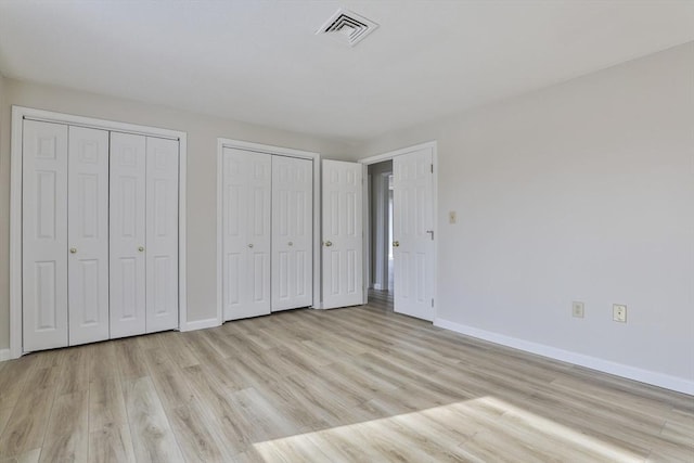 181 Littleton Rd Unit 213, Chelmsford, MA 01824 - unfurnished bedroom featuring two closets, baseboards, and light wood-style flooring