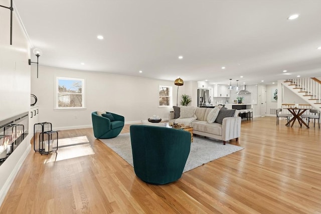 living room with light wood finished floors, baseboards, stairway, and recessed lighting