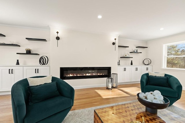 living room featuring light wood-style floors, a glass covered fireplace, crown molding, and recessed lighting