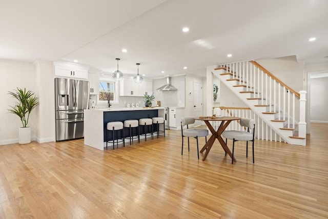 dining room with light wood-style floors, recessed lighting, and stairs