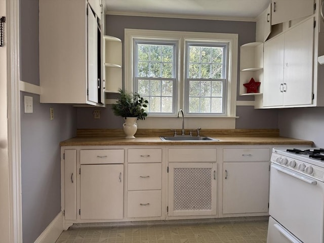 kitchen with white gas stove, sink, butcher block countertops, white cabinets, and ornamental molding