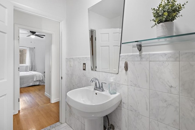 bathroom featuring hardwood / wood-style flooring, ceiling fan, sink, and tile walls