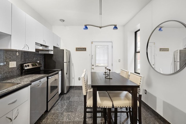 kitchen featuring backsplash, decorative light fixtures, white cabinetry, and stainless steel appliances