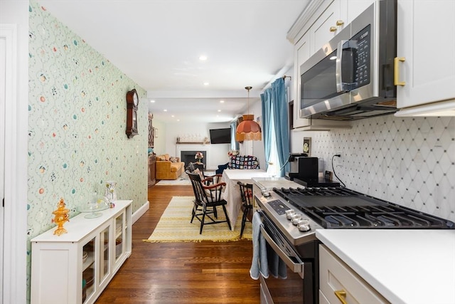 kitchen with dark wood-style flooring, appliances with stainless steel finishes, light countertops, open floor plan, and decorative backsplash