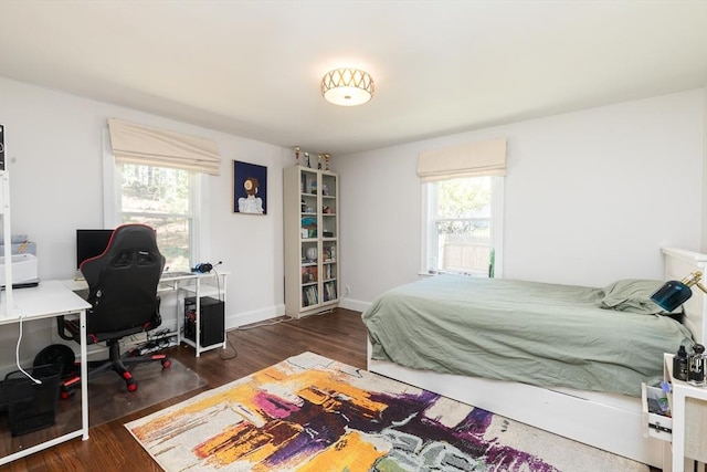 bedroom featuring baseboards, multiple windows, and wood finished floors