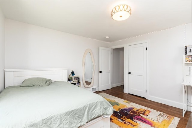 bedroom with baseboards, wood finished floors, and visible vents