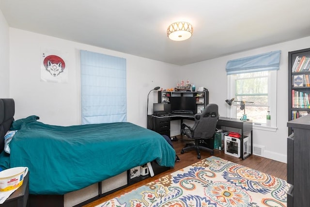bedroom with baseboards, wood finished floors, and visible vents