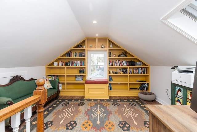 interior space with vaulted ceiling, built in features, and wood finished floors