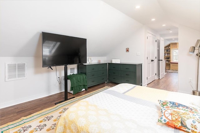 bedroom featuring visible vents, baseboards, wood finished floors, and vaulted ceiling