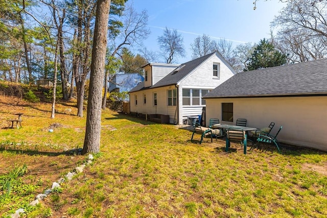 back of property featuring a yard and a shingled roof