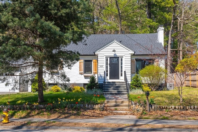 bungalow with a shingled roof, a chimney, and a front yard