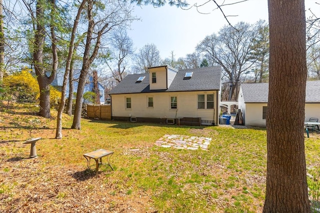 rear view of house with a lawn, central AC, fence, and a shingled roof