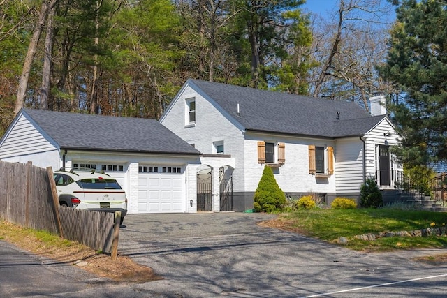 view of front of property with fence, roof with shingles, a garage, a chimney, and driveway