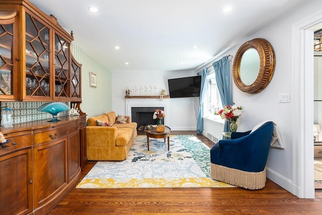 living area with a fireplace, recessed lighting, baseboards, wood finished floors, and visible vents