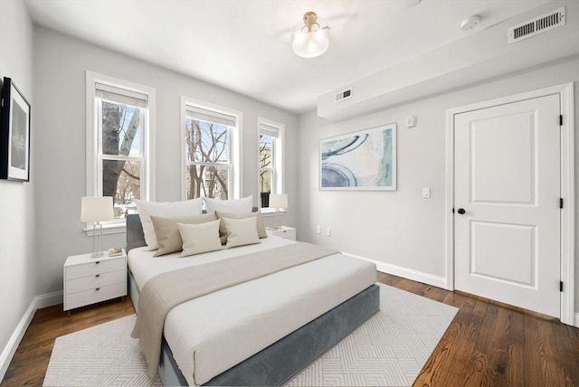 bedroom with dark wood-type flooring, visible vents, and baseboards