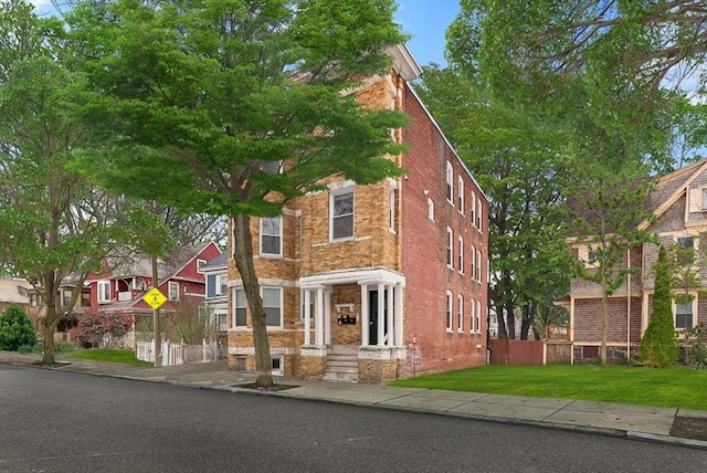 view of front of property featuring brick siding and a front lawn