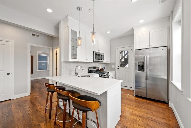 kitchen with visible vents, decorative backsplash, stainless steel appliances, a kitchen bar, and a sink