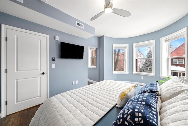 bedroom featuring multiple windows, wood finished floors, visible vents, and a ceiling fan