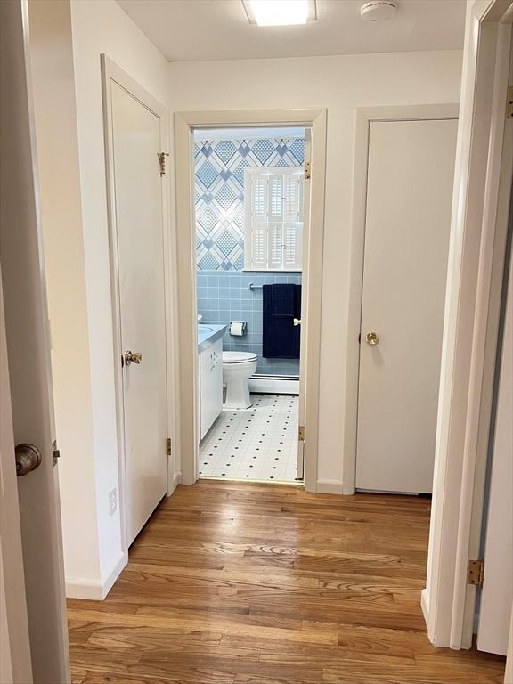 216 Bel Air Dr, Longmeadow, MA 01106 - hall with light wood-style flooring, a baseboard radiator, and tile walls