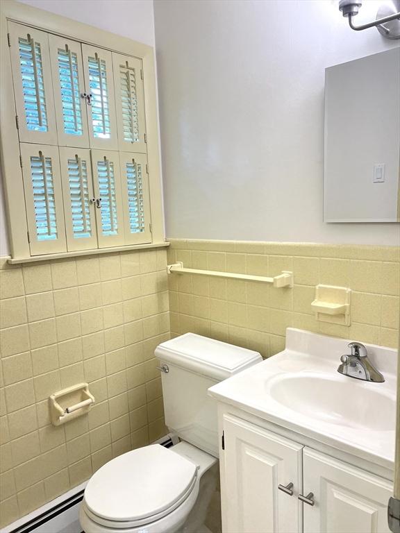 216 Bel Air Dr, Longmeadow, MA 01106 - bathroom with vanity, tile walls, a baseboard heating unit, and wainscoting