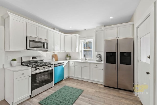 kitchen featuring sink, white cabinetry, decorative light fixtures, light wood-type flooring, and stainless steel appliances