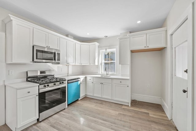 kitchen featuring sink, white cabinets, hanging light fixtures, light hardwood / wood-style floors, and stainless steel appliances