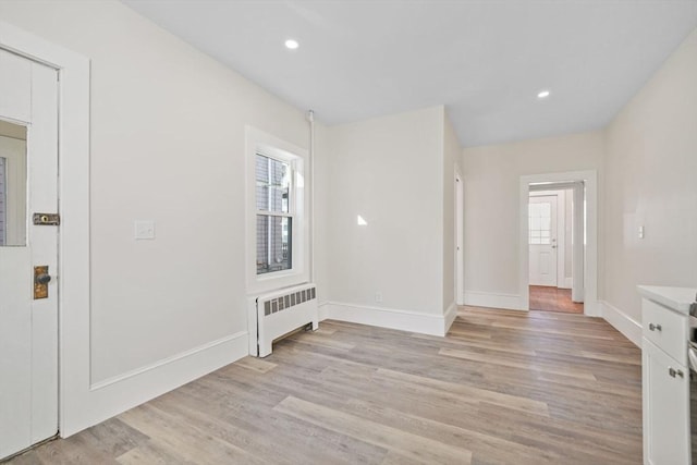 interior space with radiator heating unit, light hardwood / wood-style floors, and a healthy amount of sunlight