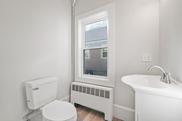 bathroom featuring radiator, wood-type flooring, and toilet