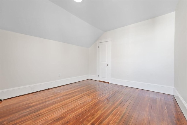 additional living space with wood-type flooring and vaulted ceiling